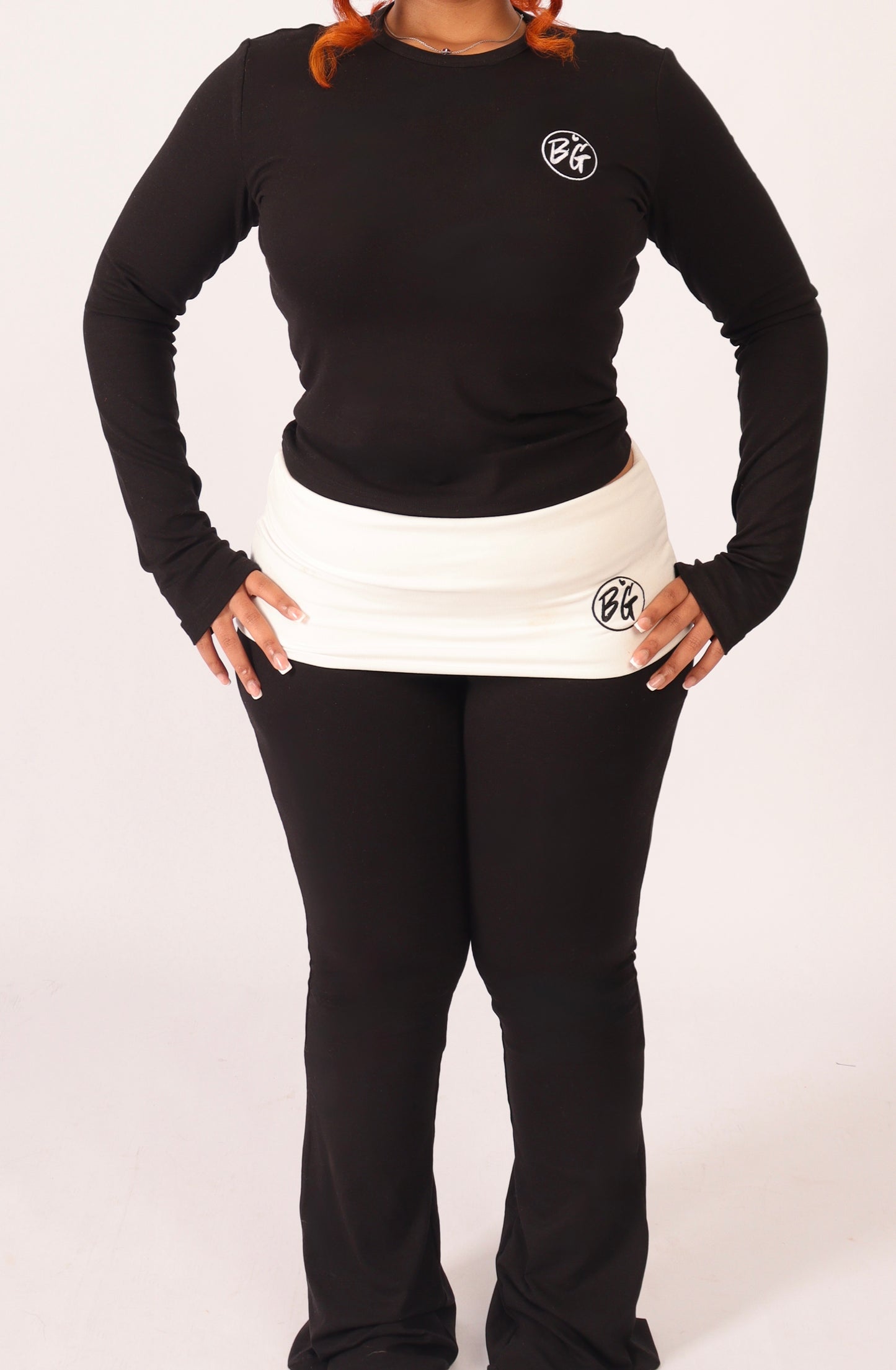 Person wearing a black long-sleeve shirt and black pants with a logo on a white background