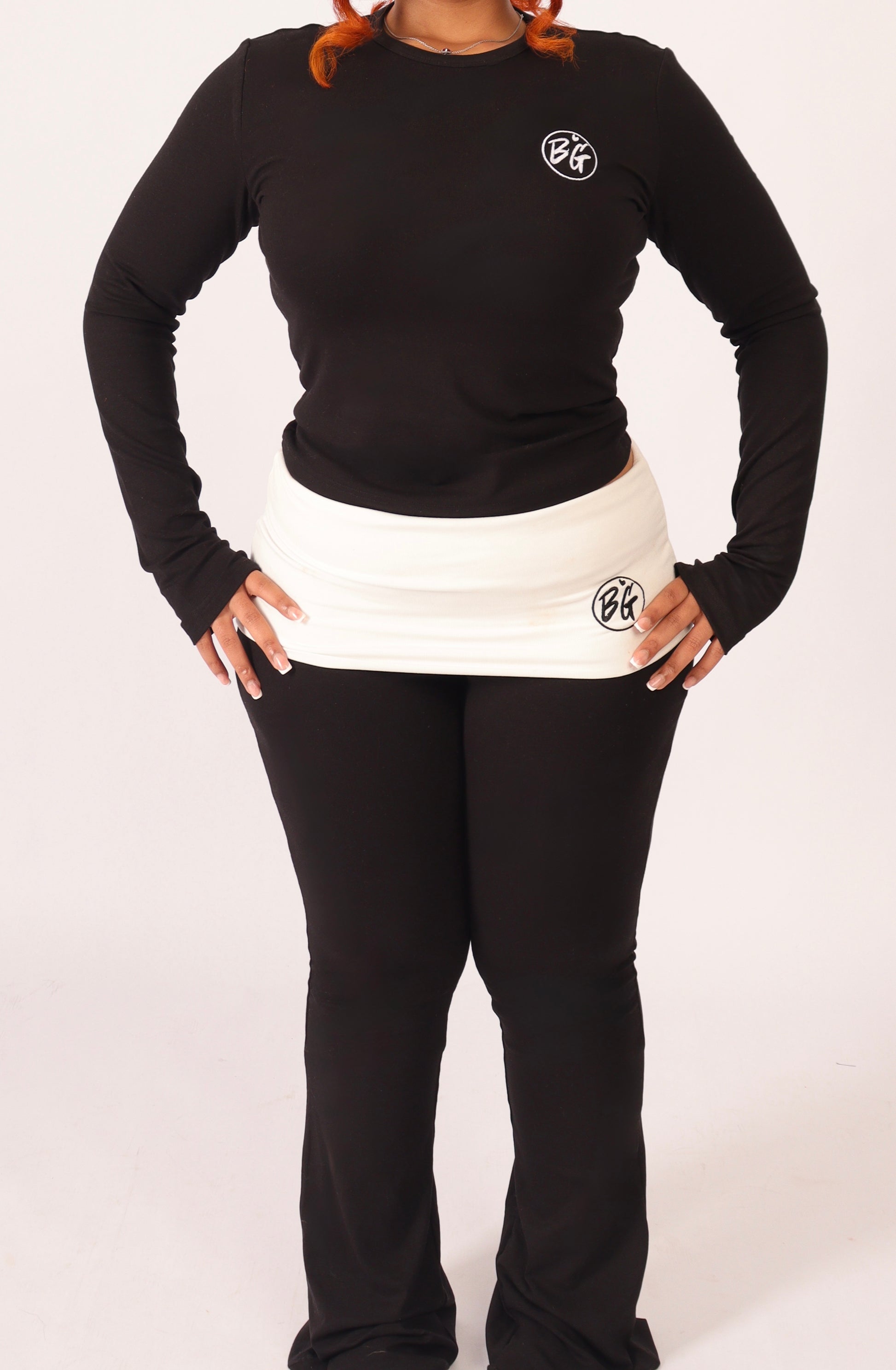 Person wearing a black long-sleeve shirt and black pants with  a logo on a white background